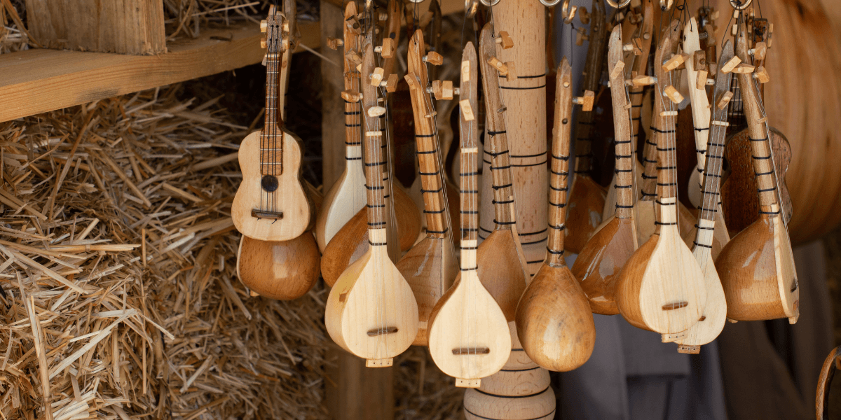 A collection of wooden string instruments hanging against a rustic background.