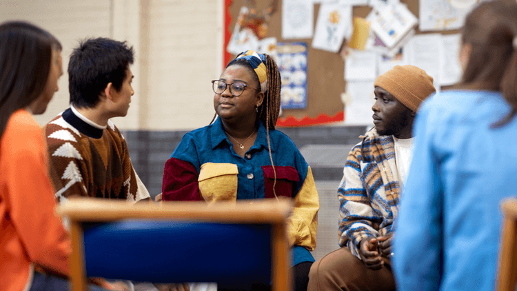 A diverse group of young people sitting in a circle engaged in conversation